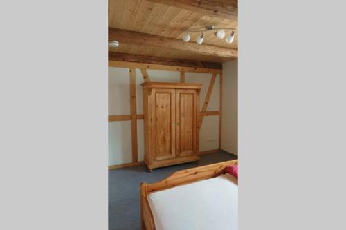 Cette chambre comprend un lit et une armoire en bois. dans l'établissement Mothsgut - moderne Ferienwohnung auf dem Bauernhof im Erzgebirge, à Oelsnitz