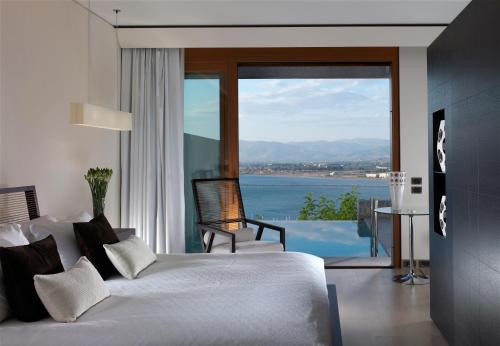 a bedroom with a bed and a view of the water at Nafplia Palace Hotel & Villas in Nafplio