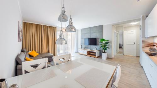 a kitchen and living room with a white table and chairs at Rezydencja Park, Sun & Snow in Mielno