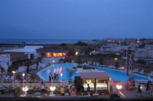 - une grande piscine avec des personnes debout la nuit dans l'établissement Naturiste Cap d'Agde Héliopolis L 24, au Cap d'Agde
