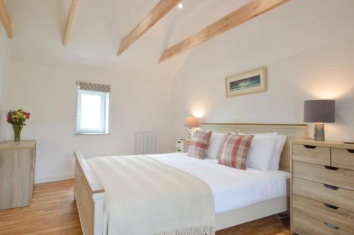 a bedroom with a white bed and a wooden dresser at Easdale Cottage in Oban