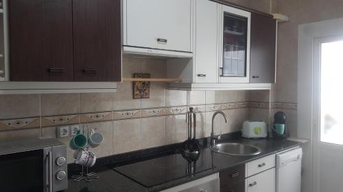 uma cozinha com armários brancos e um lavatório em LAS MARGARITAS em Gijón