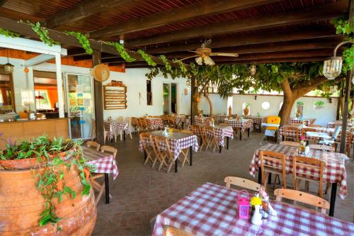 un restaurante vacío con mesas, sillas y un árbol en Kassandra Hotel, en Ialisos