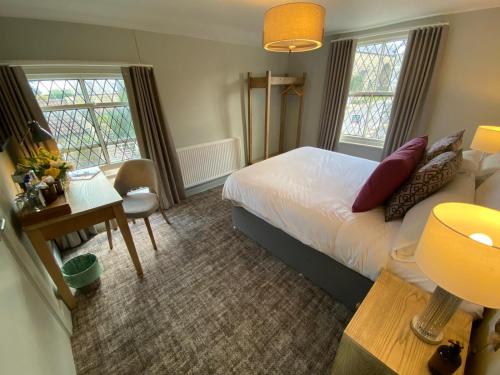 1 dormitorio con cama, mesa y escritorio en The Scotts Arms Village Inn, en Sicklinghall
