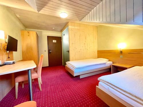 a room with two beds and a desk and a table at Boutique und Bier Hotel des alpes in Fiesch