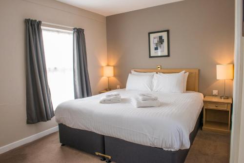 a bedroom with a large bed with two towels on it at Old Colonial, Weston-Super-Mare by Marston's Inns in Weston-super-Mare