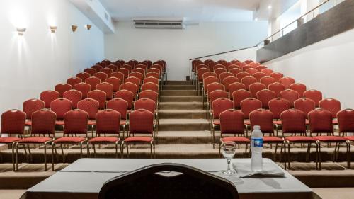 an empty auditorium with red chairs and a table with a wine glass at Hotel Metropol in San Miguel de Tucumán