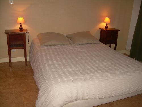 un grande letto bianco con due lampade su due tavoli di gite a la ferme cavaroz a Bracon