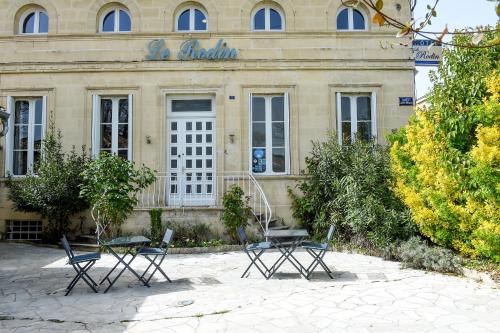 un bâtiment avec deux tables et des chaises devant lui dans l'établissement Le Rodin Bazas, à Bazas