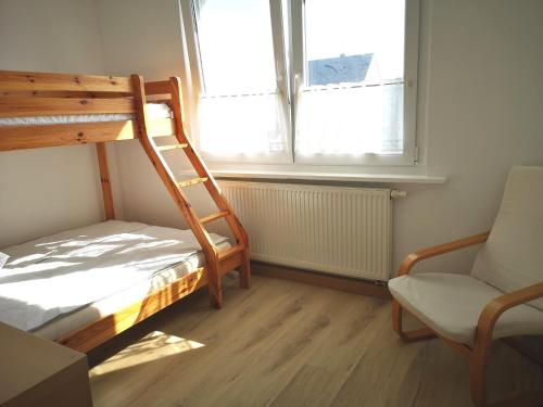 a bedroom with a bunk bed and a chair and a window at Sommerhaus Verchen in Verchen