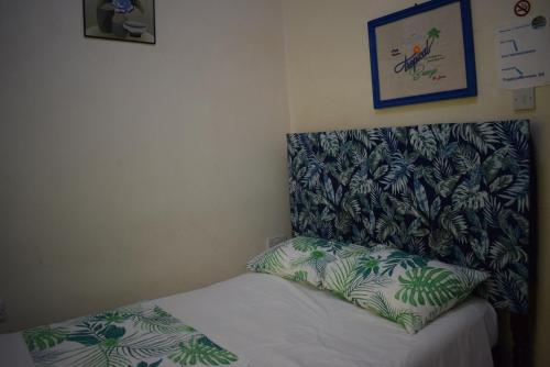 a small bedroom with a bed with a green patterned headboard at Tropical Breeze Vacation Home and Apartments in Gros Islet