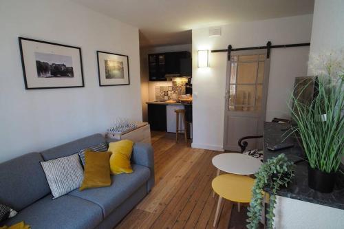 un salon avec un canapé bleu et une cuisine dans l'établissement STUDIO BRICK AND WOOD - HYPERCENTRE - TV - WIFI, à Toulouse