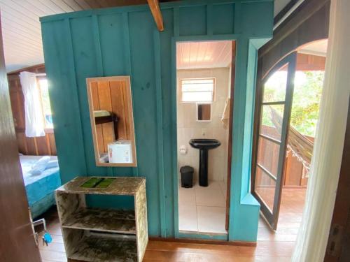 a small bathroom with a blue wall and a mirror at Pousada Recanto Tropical in Ilha do Mel