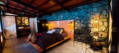 a bedroom with a bed and a stone wall at EL PICNIC ATITLÁN in Tzununá