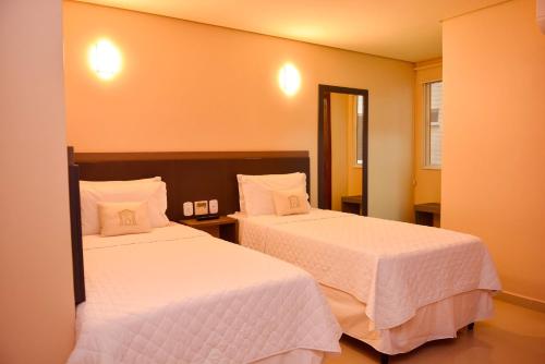 Habitación de hotel con 2 camas con sábanas blancas en Forte Express en Macapá