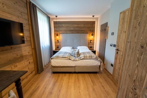 a bedroom with a bed and a flat screen tv at Hotel Alpenrose Wellness in Vattaro