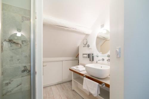 a white bathroom with a sink and a shower at Logis - Hotel De La Mairie in Embrun