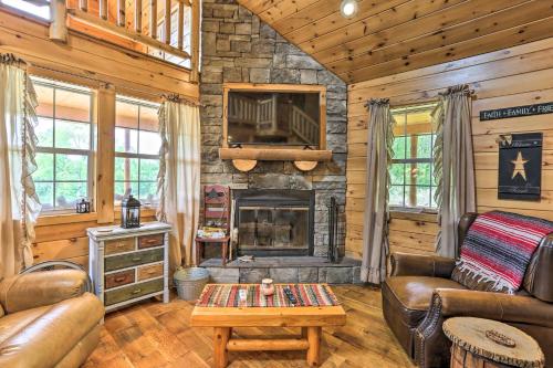 a living room with a stone fireplace in a log cabin at Porch, Fire Pit and Valley Views Blakely Cabin! in Blakely
