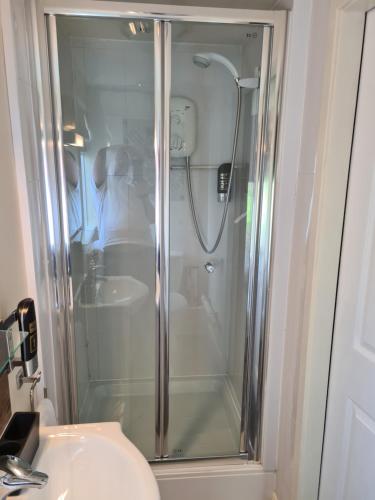 a shower with a glass door next to a sink at Tudor Lodge Hotel in Nottingham