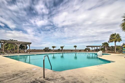 a large swimming pool with palm trees and a cloudy sky at Harbor Island Beach Retreat - Steps to Ocean! in Oceanmarsh Subdivision