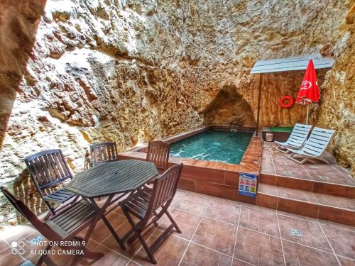 uma piscina numa gruta com uma mesa e cadeiras em Town House with Private Pool in Village Centre em Kalkara