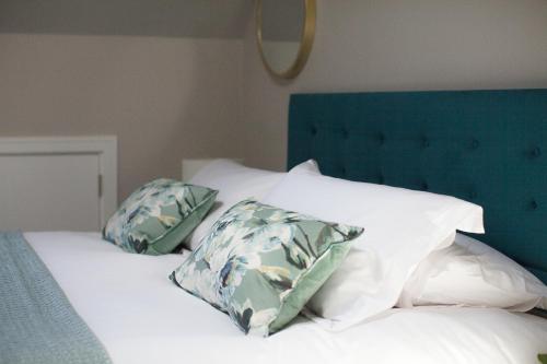 a bed with white pillows and a blue headboard at The Loft, Bootham House - luxury city centre apartment with parking space in York