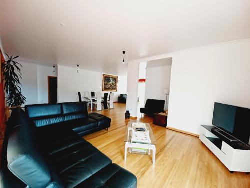 a living room with a black leather couch and a table at Villa Luz - Family House Vacations- Large Private Outdoor Area in Santa Cruz