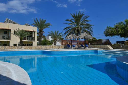 a swimming pool in a resort with palm trees at Galini Apartments in Achlia