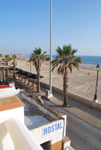 a beach with palm trees and a hospital sign at Tranvía Beach House in Chipiona