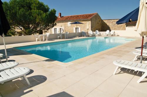 une piscine avec des chaises et une maison dans l'établissement Le Vieux Monastere, à Saint-Hilaire-de-Villefranche