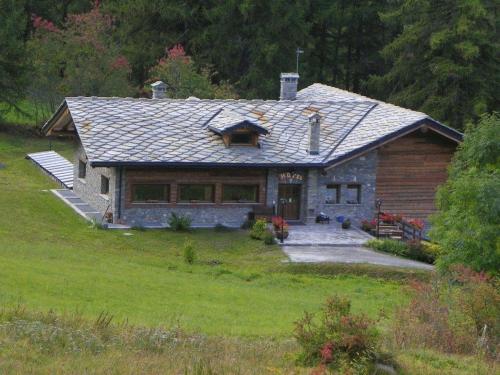a log home with a porch on a lawn at Hotel Les Granges in La Thuile