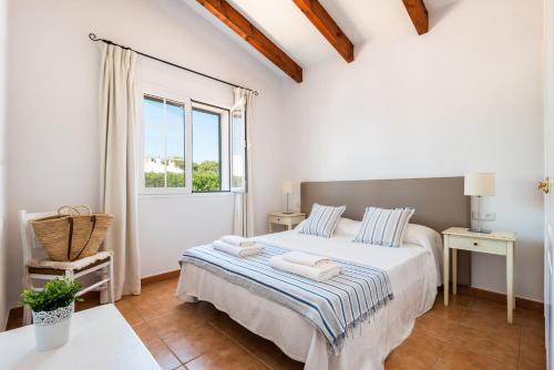 ein weißes Schlafzimmer mit einem Bett und einem Fenster in der Unterkunft Casa Bruna - Binibeca Nou in Sant Lluís