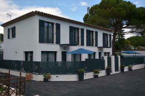 a white building with black windows and umbrellas at Les villas du Golf Mougins in Mougins