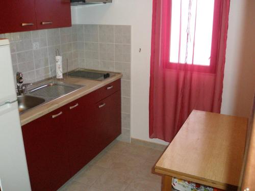 a kitchen with a sink and a red curtain at Apartment Borik in Zadar