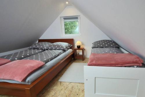 2 camas individuales en un dormitorio en el ático en Drewniany domek nad jeziorem w Sitnie, en Sitno