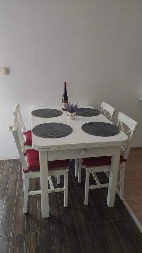 a white table with chairs and a bottle of wine at Apartmani Maslina Žuljana in Žuljana
