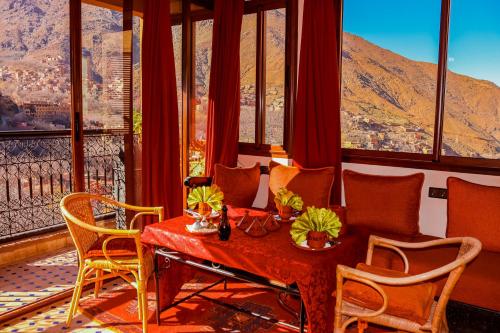 Cette chambre comprend une table, des chaises et des fenêtres. dans l'établissement Riad Atlas Toubkal, à Imlil