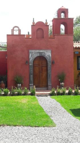 a red house with a wooden door and a yard at Casa Loteria in San Miguel de Allende