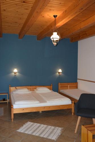 a bedroom with a bed and a blue wall at Nyitott Kapu Vendégház in Felsőtárkány