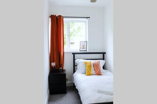 - une chambre avec un lit doté de rideaux orange et d'une fenêtre dans l'établissement Chic Beach Getaway (sleeps 6) - 4min walk to beach, à Kent