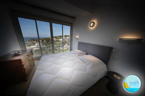 1 dormitorio con cama blanca y ventana grande en UNE TERRASSE SUR LA MER 3 pers 2 chambres VUE MER, en Cassis