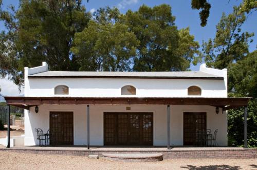 an old white building with two garage doors at Ongegund Lodge in Somerset West