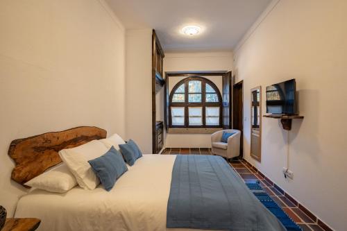 Schlafzimmer mit einem Bett, einem TV und einem Fenster in der Unterkunft Escola do Fado in Vila Fernando