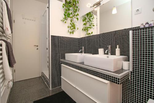 uma casa de banho com 2 lavatórios e paredes em azulejo preto em Carrera Corner Apartment em Rovinj