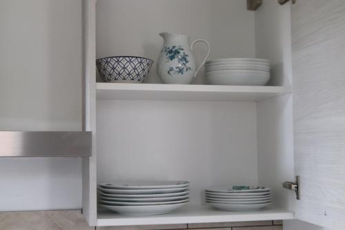 a shelf with plates and a vase and dishes at Chambres d'hôtes "HOR DAGO" près de la gare d'Hendaye avec le petit-déjeuner in Hendaye