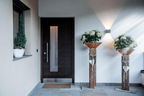 two vases with flowers on them in front of a door at Apartment Schifta in Chienes