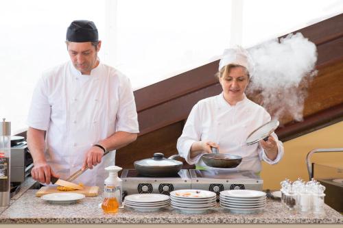 a man and woman in a kitchen preparing food at Hotel Torino Wellness & Spa in Diano Marina