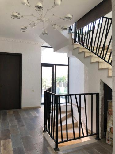 a living room with a staircase and a chandelier at TJ GARDENS in Makhinjauri