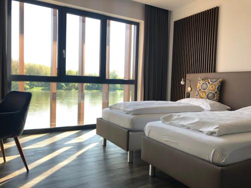 a hotel room with three beds and a large window at Hotel Donauhof Mauthausen in Mauthausen