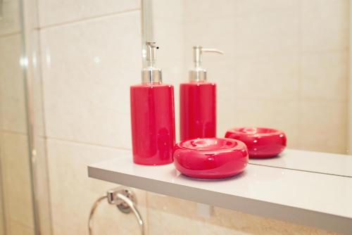 two red candles sitting on a shelf in a bathroom at Makara in Katowice
